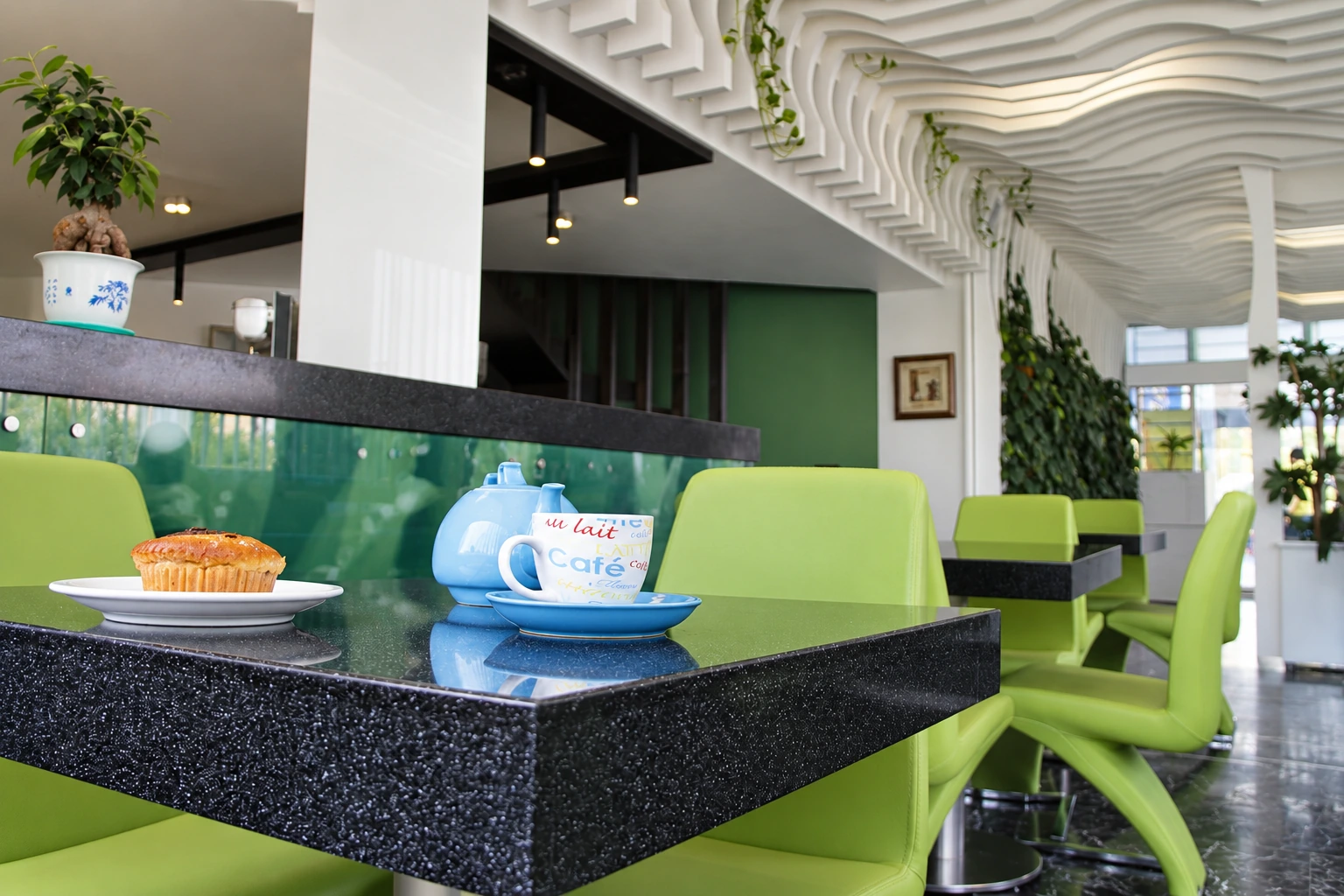Main view of Atiyeh Hospital Café with sculptural wave ceiling, green seating and black stone tables