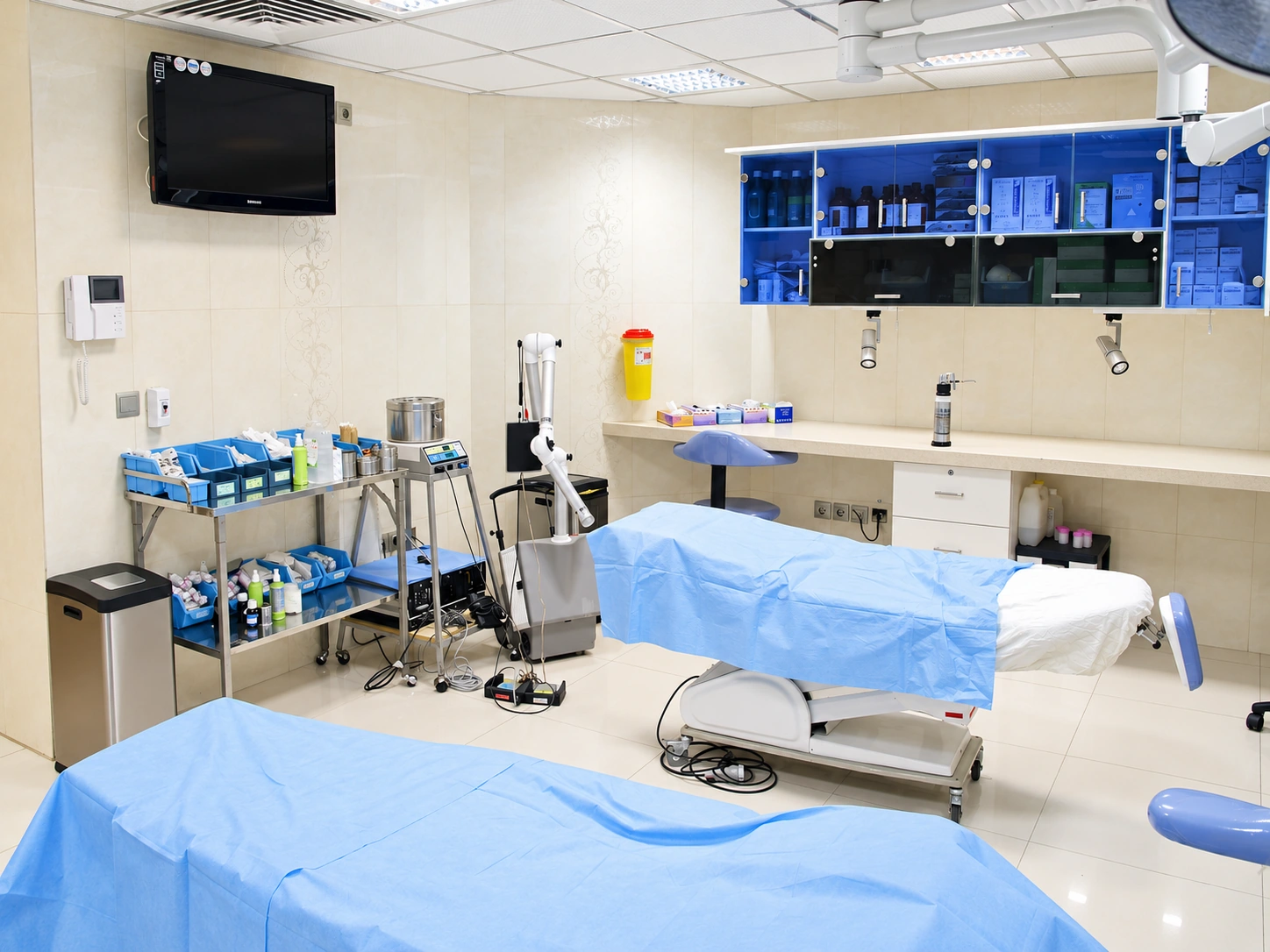 Procedure room at Baqiyatallah Hospital Dermatology and Hair Clinic with two treatment beds and blue cabinetry