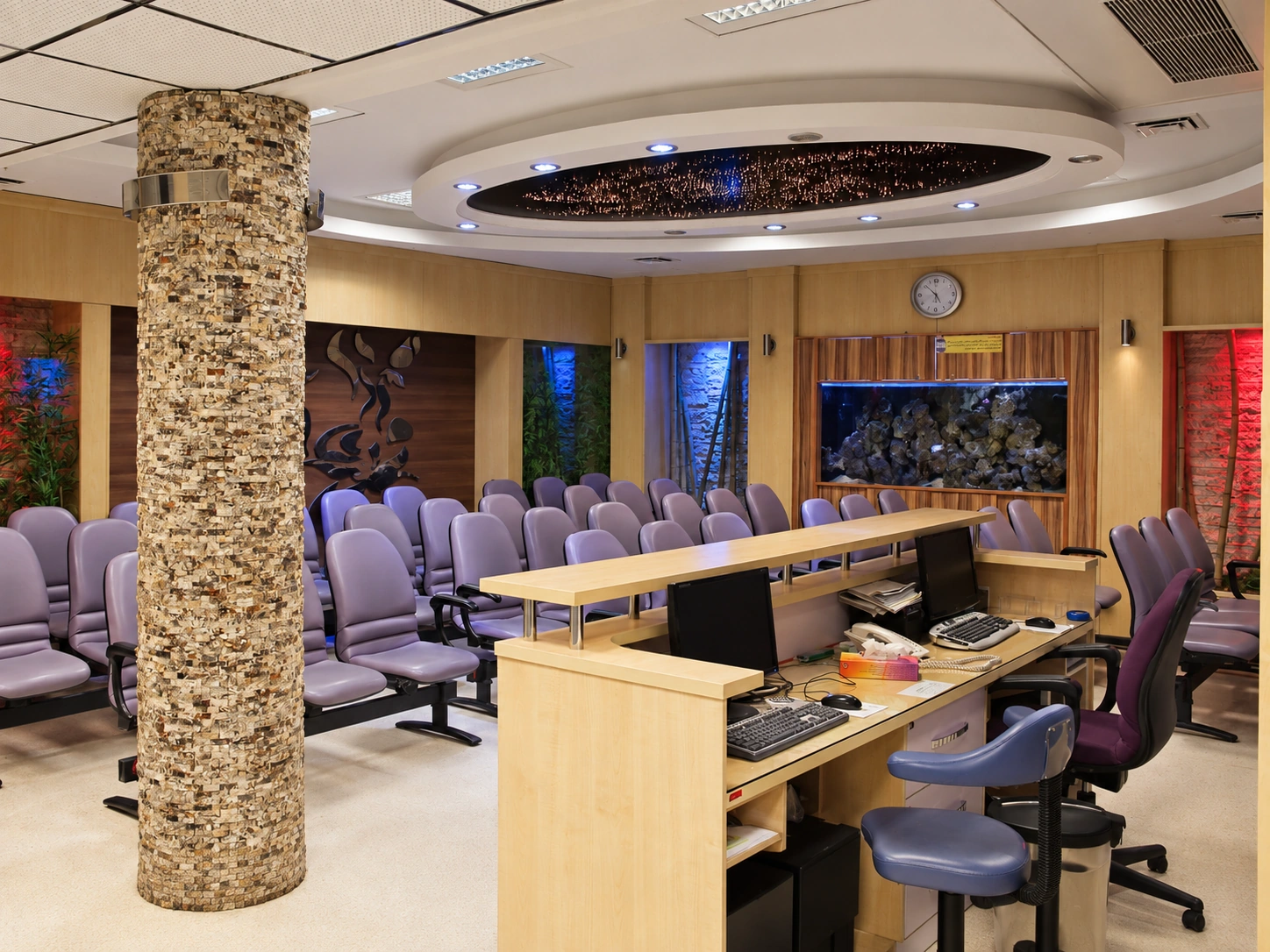Reception and waiting area at Baqiyatallah Hospital Dermatology and Hair Clinic with purple seating, aquarium and curved illuminated ceiling