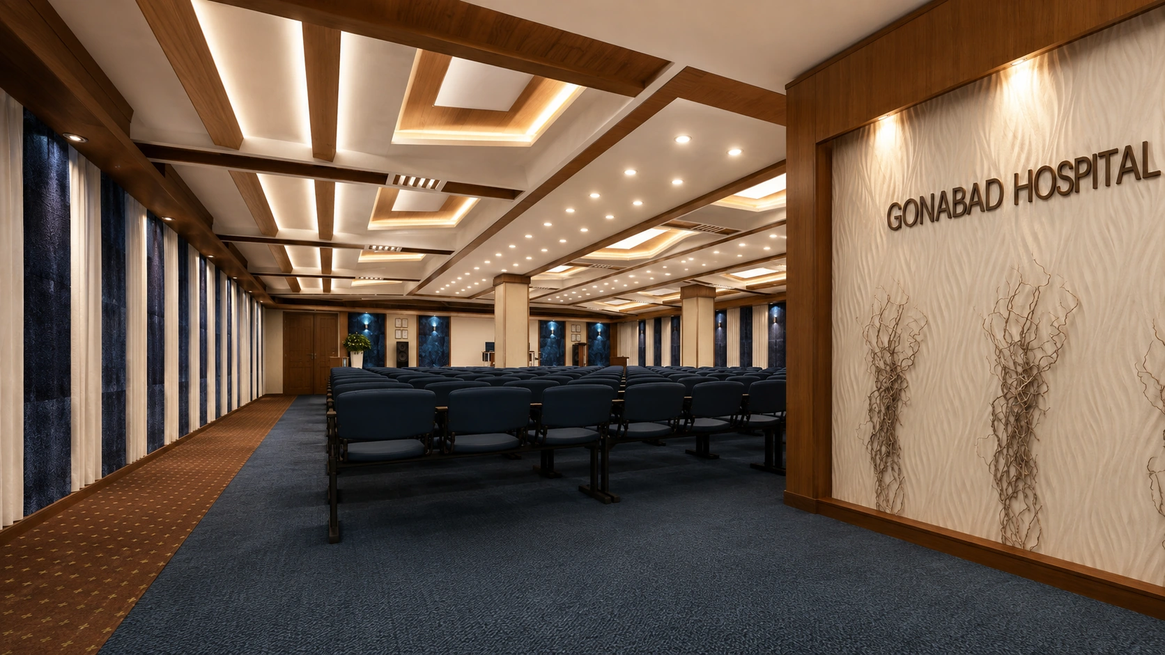 Rear view of Behloul Gonabadi Hospital auditorium showing seating rows, layered timber ceiling and illuminated wall signage