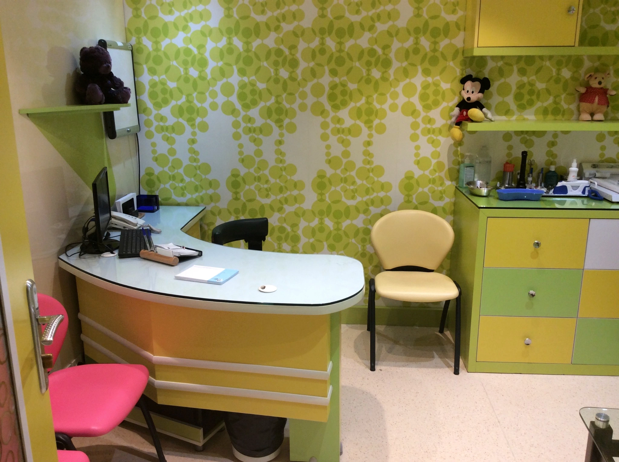 Curved workstation in the Day Hospital pediatric clinic with patterned green wall and integrated office equipment
