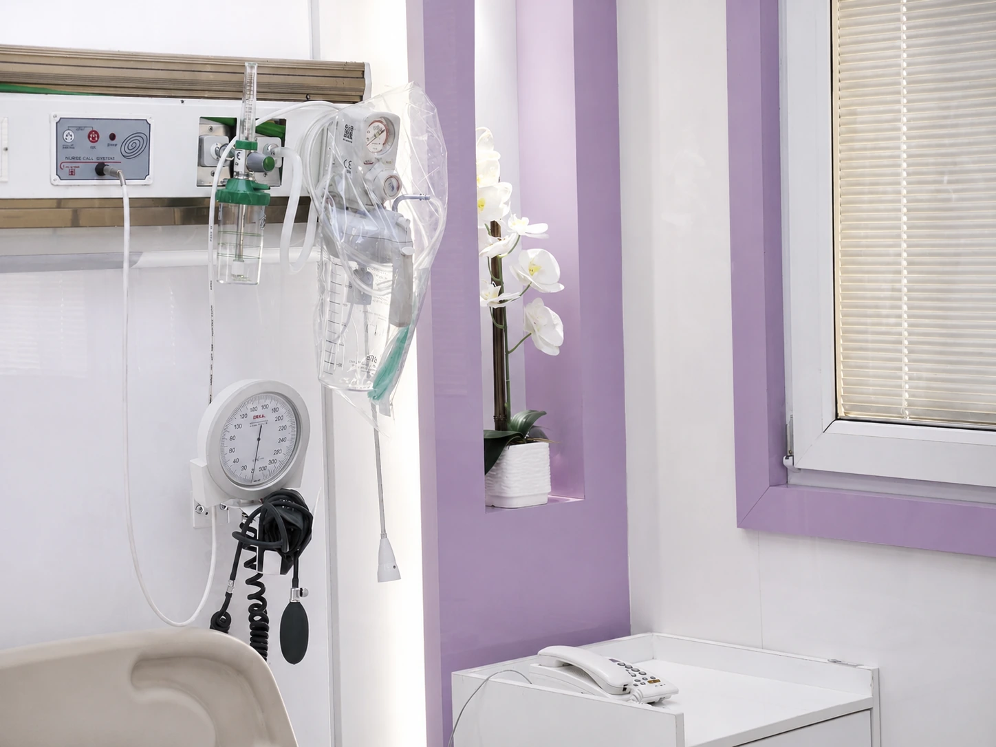 Medical-service headwall detail in the Purple VIP patient room at Day Hospital with bedside equipment and lavender wall accents